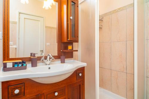 La salle de bains est pourvue d'un lavabo, d'un miroir et d'une douche. dans l'établissement Le 100 Sculture Apartment, à Belpasso