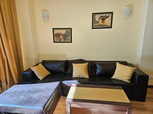 a living room with a black leather couch and a table at TERRA KOMPLEX D3 - Private apartment - Golf, Skiing & SPA in Razlog