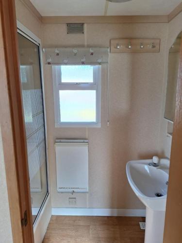 een badkamer met een wastafel en een raam bij Thornbury Holiday Park in Thornbury