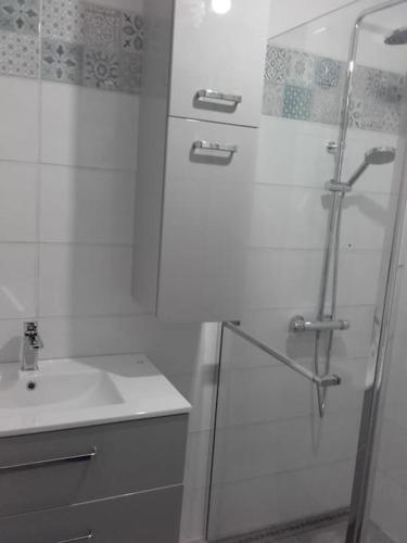 une salle de bain blanche avec une douche et un lavabo dans l'établissement Maison de vacances 4/5 personnes à Léon, Landes, à Léon