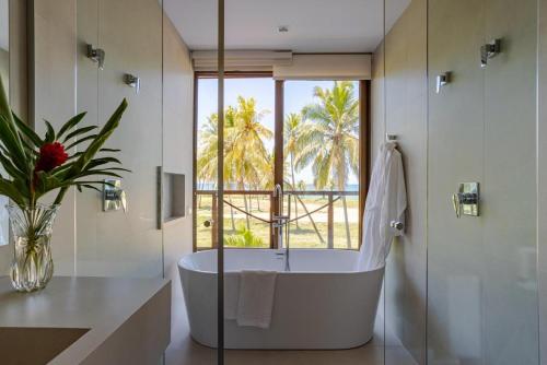 uma casa de banho com banheira e uma grande janela em Luxo a 50 m da praia, acesso ao Iberostar Resort na Praia do Forte