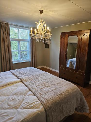 a bedroom with a large bed and a chandelier at Logeerderij tussen Koe & Kroonluchter in Diessen