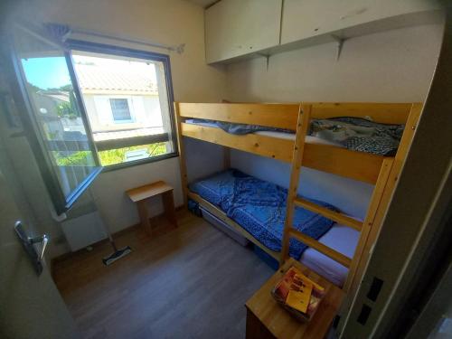 une petite chambre avec deux lits superposés et une fenêtre dans l'établissement HOLIDAYLAND CALAMAR PAVILLON T2 6 couchages climatisé Narbonne Plage, à Narbonne-Plage