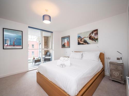um quarto branco com uma cama grande e uma janela em London Apartment near Tower Bridge and Tube Pass the Keys em Londres