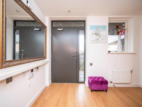uma sala de estar com um repousa-pés roxo e um espelho em London Apartment near Tower Bridge and Tube Pass the Keys em Londres