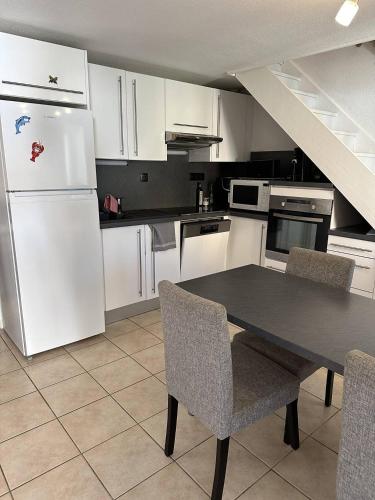 - une cuisine avec des appareils blancs, une table et des chaises dans l'établissement HOLIDAYLAND 432 VILLA T2 MEZZANINE 6 couchages climatisé avec véranda et Box internet NARBONNE PLAGE, à Narbonne-Plage