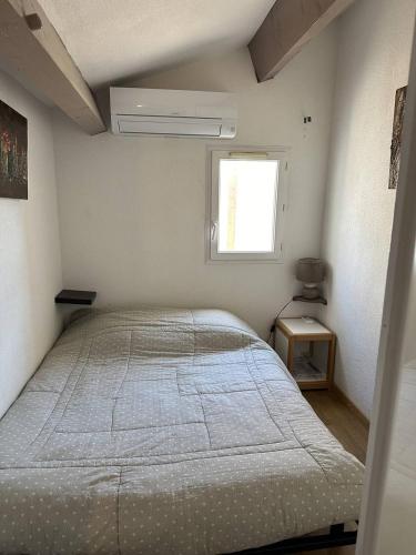 1 dormitorio con cama y ventana en HOLIDAYLAND 432 VILLA T2 MEZZANINE 6 couchages climatisé avec véranda et Box internet NARBONNE PLAGE, en Narbonne-Plage
