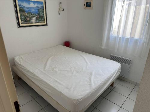 un lit blanc dans une chambre avec une fenêtre dans l'établissement HOLIDAYLAND 202 VILLA T3 MEZZANINE 6 couchages NARBONNE PLAGE, à Narbonne-Plage
