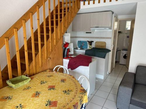 - une cuisine et une salle à manger avec une table et des escaliers dans l'établissement HOLIDAYLAND 202 VILLA T3 MEZZANINE 6 couchages NARBONNE PLAGE, à Narbonne-Plage