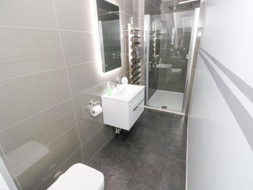 テンビーにあるApartment 4の白い洗面台とシャワー付きのバスルーム