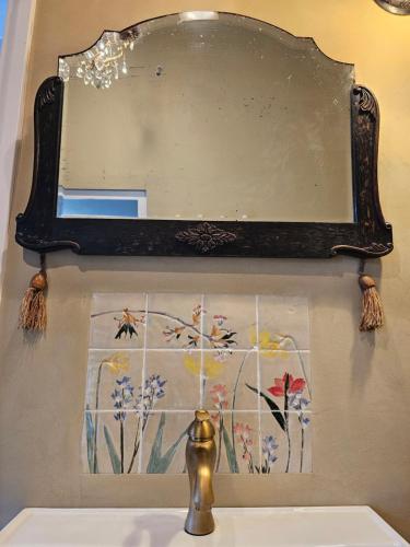 un espejo en la pared sobre un lavabo en Logeerderij tussen Koe & Kroonluchter en Diessen