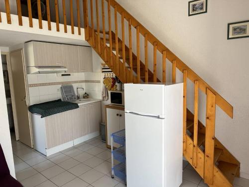 une cuisine avec un réfrigérateur blanc et un escalier dans l'établissement HOLIDAYLAND 201 VILLA T3 MEZZANINE 8 couchages climatisé NARBONNE PLAGE, à Narbonne-Plage