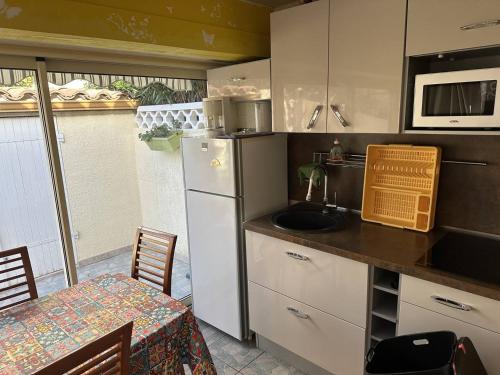 La cuisine est équipée d'un évier, d'un réfrigérateur et d'une table. dans l'établissement HOLIDAYLAND 318 VILLA T2 MEZZANINE 4 couchages climatisé avec véranda NARBONNE PLAGE, à Narbonne-Plage