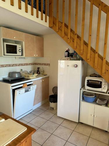 une cuisine avec un réfrigérateur blanc et un escalier dans l'établissement HOLIDAYLAND 420 VILLA T3 MEZZANINE 8 couchages climatisé NARBONNE PLAGE, à Narbonne-Plage