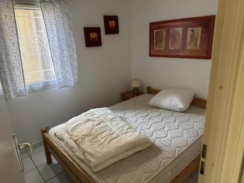 une chambre avec un lit avec des draps blancs et une fenêtre dans l'établissement HOLIDAYLAND 251 VILLA T2 MEZZANINE 6 couchages NARBONNE PLAGE, à Narbonne-Plage