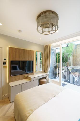a bedroom with a large bed and a tv at Holland Park Residence in London