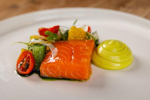 a white plate with a piece of salmon and vegetables at The Northumberland Arms in West Thirston