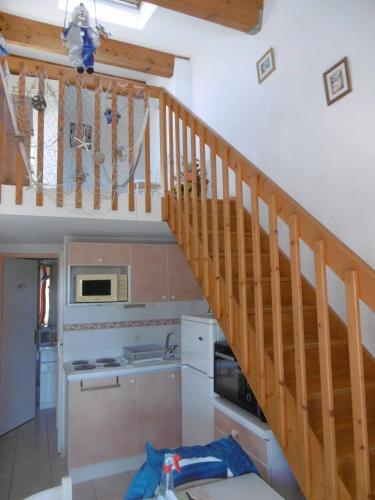 une cuisine avec un escalier en bois dans une maison dans l'établissement HOLIDAYLAND 401 VILLA T3 MEZZANINE 7 couchages climatisé NARBONNE PLAGE, à Narbonne-Plage