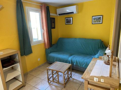 - un salon avec un canapé bleu et des murs jaunes dans l'établissement HOLIDAYLAND 323 VILLA T2 MEZZANINE 8 couchages climatisé NARBONNE PLAGE, à Narbonne-Plage