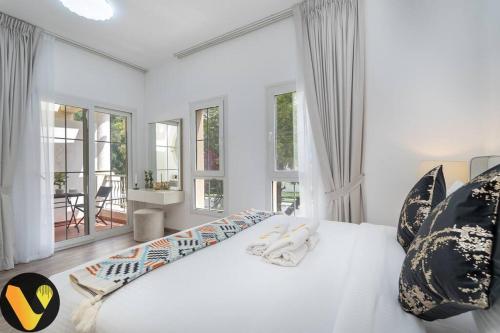 a white bedroom with a large bed and windows at Vogue Villa Near Golf/Ski Dubai/ Ibn Battuta Mall in Dubai