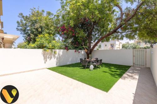 a garden with a table and chairs and a fence at Vogue Villa Near Golf/Ski Dubai/ Ibn Battuta Mall in Dubai