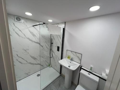 baño blanco con ducha y lavamanos en Fully Furnished Medway with FREE PARKING by Prescott Apartments, en Bristol