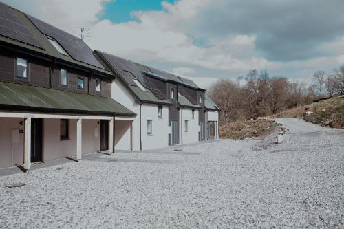 a row of white buildings with a gravel driveway at Mews by the tay in Aberfeldy