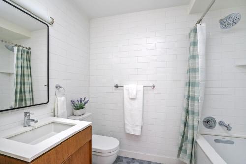 a white bathroom with a sink and a toilet at Luxurious 2 BR Apartment in New York in New York
