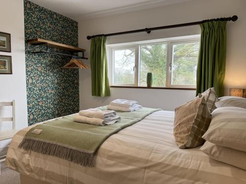 Schlafzimmer mit einem großen Bett und grünen Vorhängen in der Unterkunft Ritson Farm - Large Traditional Farm House in Totnes