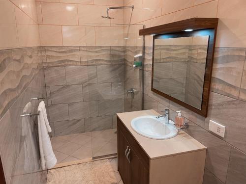 y baño con lavabo y ducha con espejo. en Sky Suites Osu en Accra