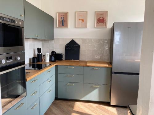 La cuisine est équipée de placards bleus et d'un réfrigérateur en acier inoxydable. dans l'établissement St Malo - Rothéneuf, proche Mont St Michel et Cancale, grande maison familiale, à Saint-Malo