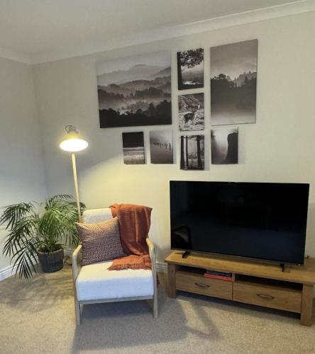 a living room with a flat screen tv and a chair at Island View - Spacious Two Bedroom Oban Apartment with Sea Views in Oban
