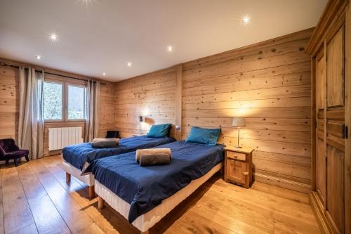 1 dormitorio con paredes de madera y 1 cama con sábanas azules en Chalet L'aube claire - 5 étoiles en Morzine