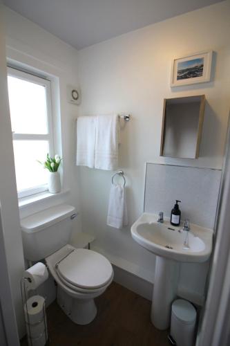 a white bathroom with a toilet and a sink at Island View - Spacious Two Bedroom Oban Apartment with Sea Views in Oban
