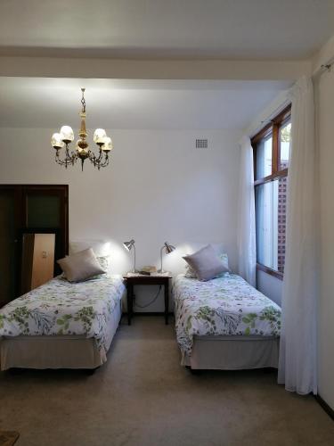 a bedroom with two beds and a table with a chandelier at The Broad Place in Worcester