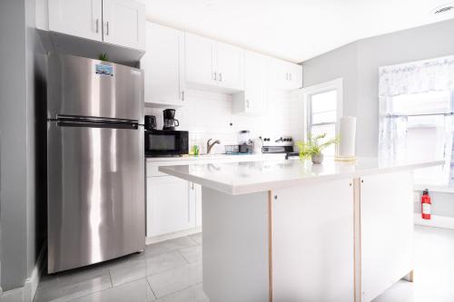 a kitchen with white cabinets and a stainless steel refrigerator at The Maid of the Mist Villa- With Private Yard & Parking, Minutes From Falls & Casino by Niagara Hospitality in Niagara Falls