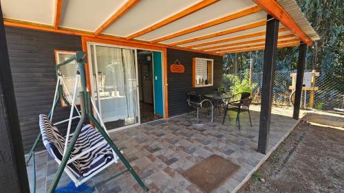 a patio with a swing and a table on it at Las palmeras de Colbún in Colbún