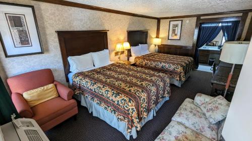 a hotel room with two beds and a chair at Edelweiss Inn New Braunfels in New Braunfels