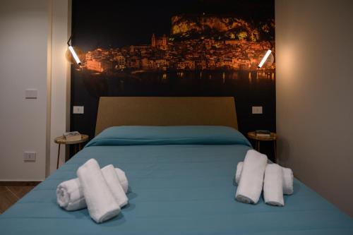 - une chambre avec un lit bleu et des serviettes dans l'établissement INCAO HOLIDAY LA STRUMMULA HOUSE, à Cefalù