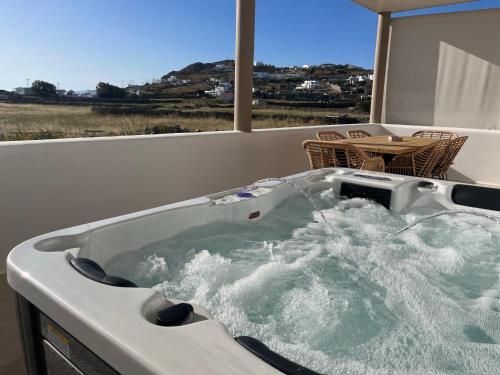 a jacuzzi tub on a balcony with a table at Gaia Mykonos Villas & Suites in Tagou