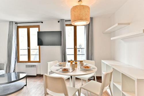 une salle à manger blanche avec une table et des chaises blanches dans l'établissement Appartement paisible et central Rivoli, à Paris