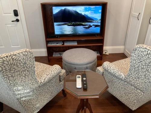 uma sala de estar com duas cadeiras e uma televisão em The Red House Fredericton em Fredericton