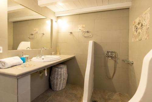 a bathroom with a sink and a shower and a mirror at Pauvre Maison with sea View in Chrisopigi