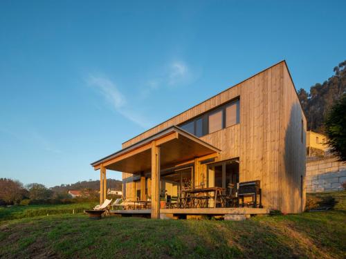 una casa de madera en una colina con un campo de hierba en Doni Wood House, casa en la playa de Doniños, en A Coruña