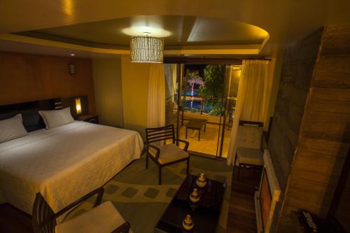 a bedroom with a bed and a chair and a window at Eco Resort Serra Imperial in São Pedro da Serra