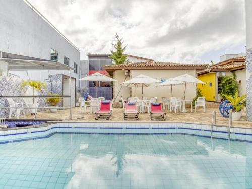 a swimming pool with chairs and umbrellas next to a house at Hotel Park Stella Mares in Salvador