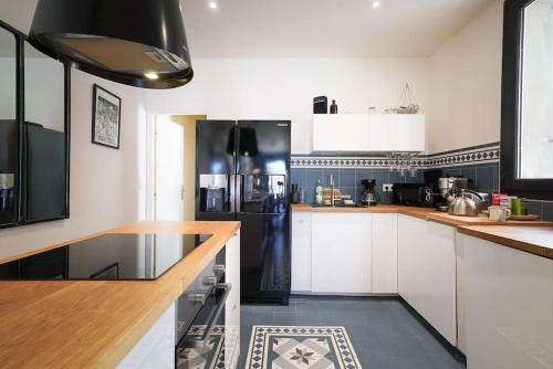 une cuisine avec des armoires blanches et un réfrigérateur noir dans l'établissement Le Balcon de la Comédie, Beau T3 Centre Historique, à Montpellier