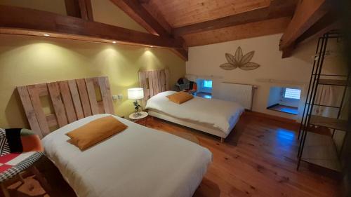 1 dormitorio con 2 camas en una habitación con suelo de madera en Gîtes Le Triskèle en Rochepaule