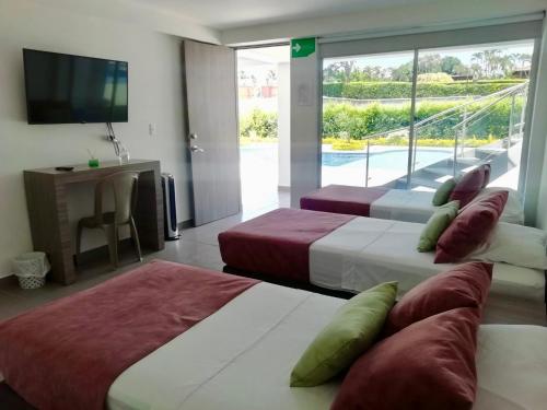 dwa łóżka w pokoju z telewizorem w obiekcie Finca Hotel Santa Catalina w mieście La Rochela