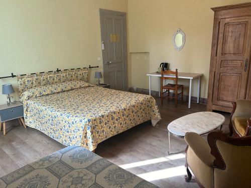 a bedroom with a bed and a table and a chair at Le Parc aux Cedres in Laroque